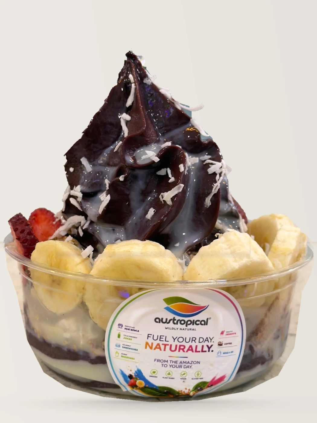 A swirl of açaí with a white drizzle and coconut over banana, on the café counter.